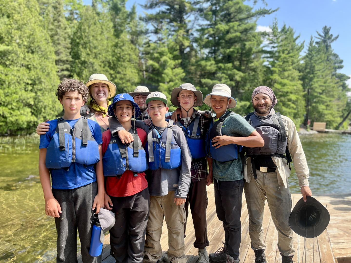 Group of people wearing life jackets near a lake.