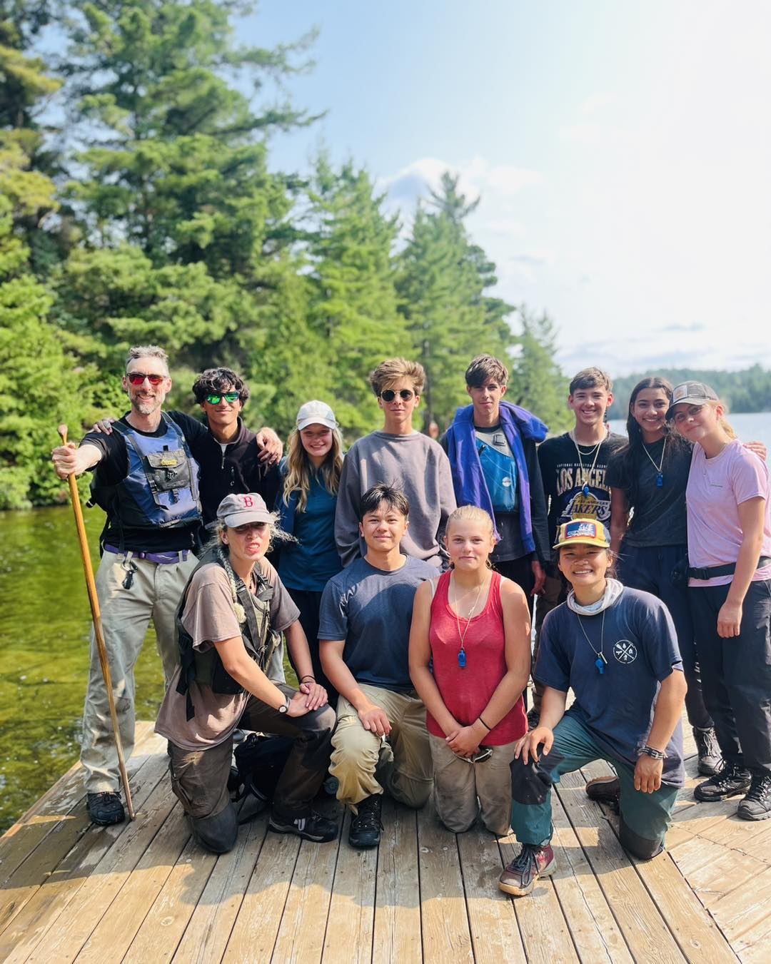 Group of people on wooden dock by lake.