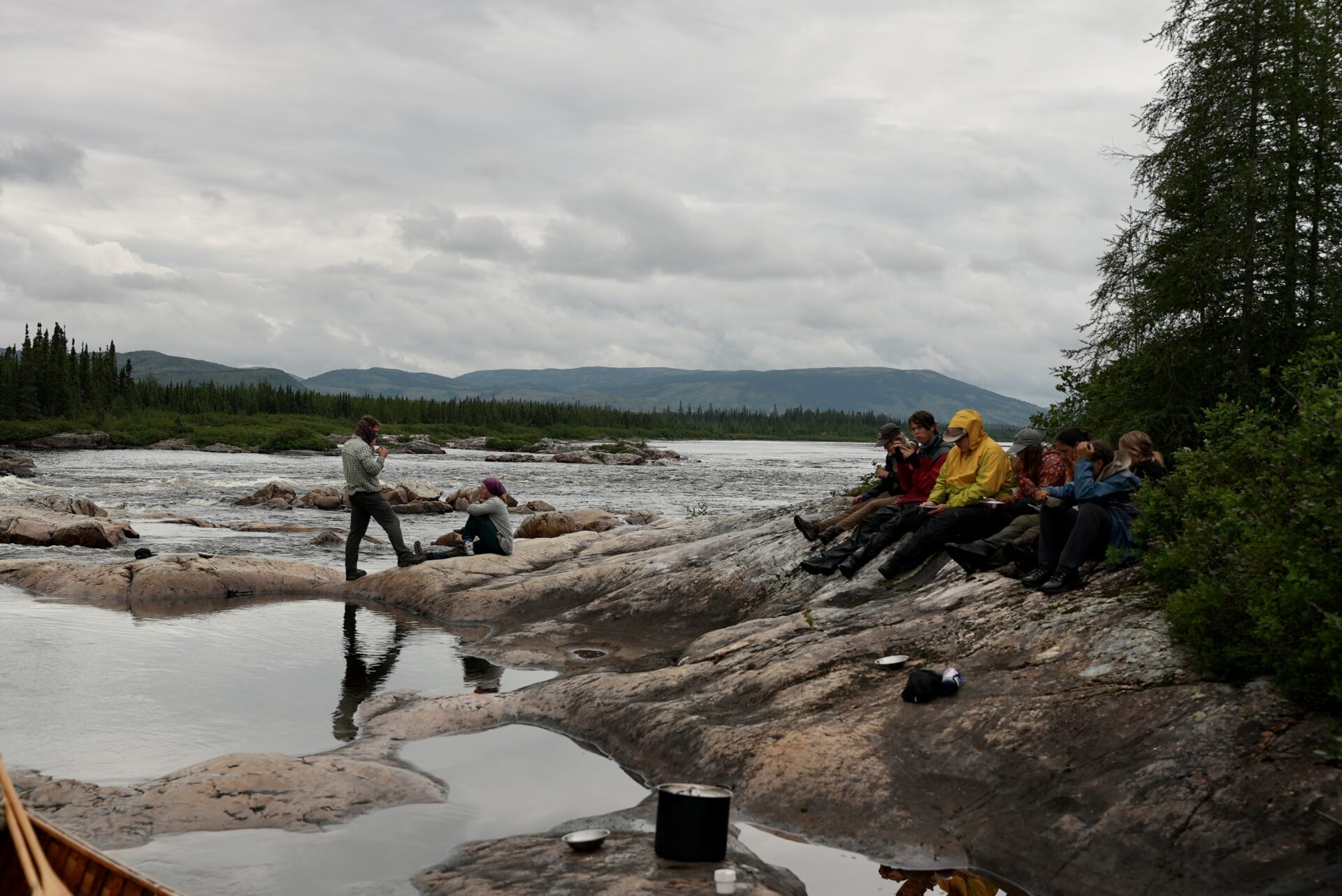 Group relaxing by river in natural landscape.