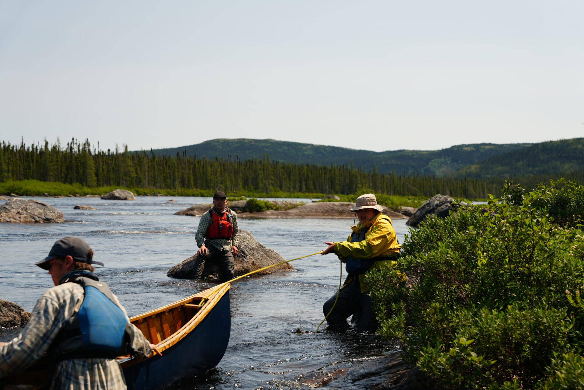 Men maneuvering a canoe in a river.