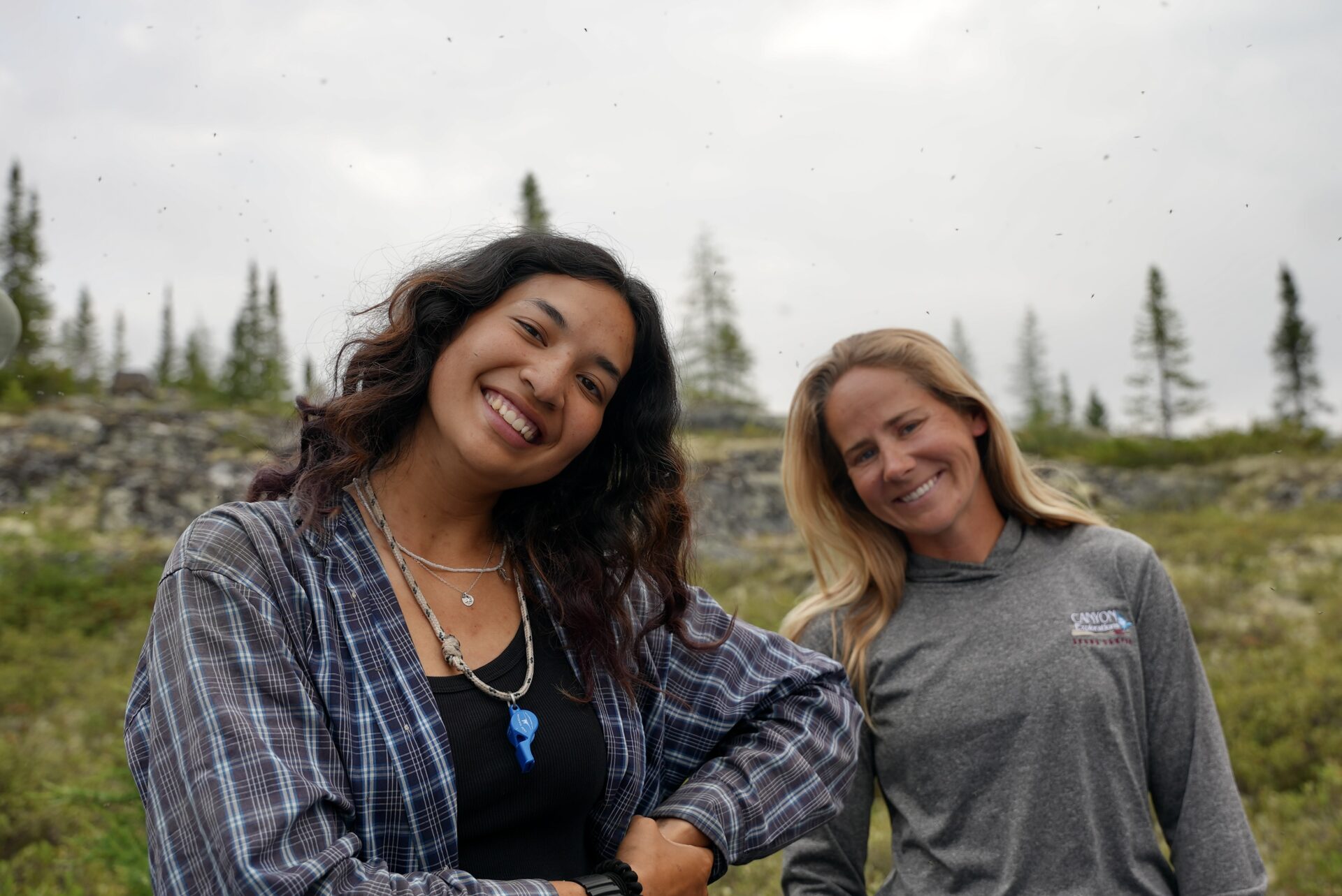 Two women smiling outdoors in nature.