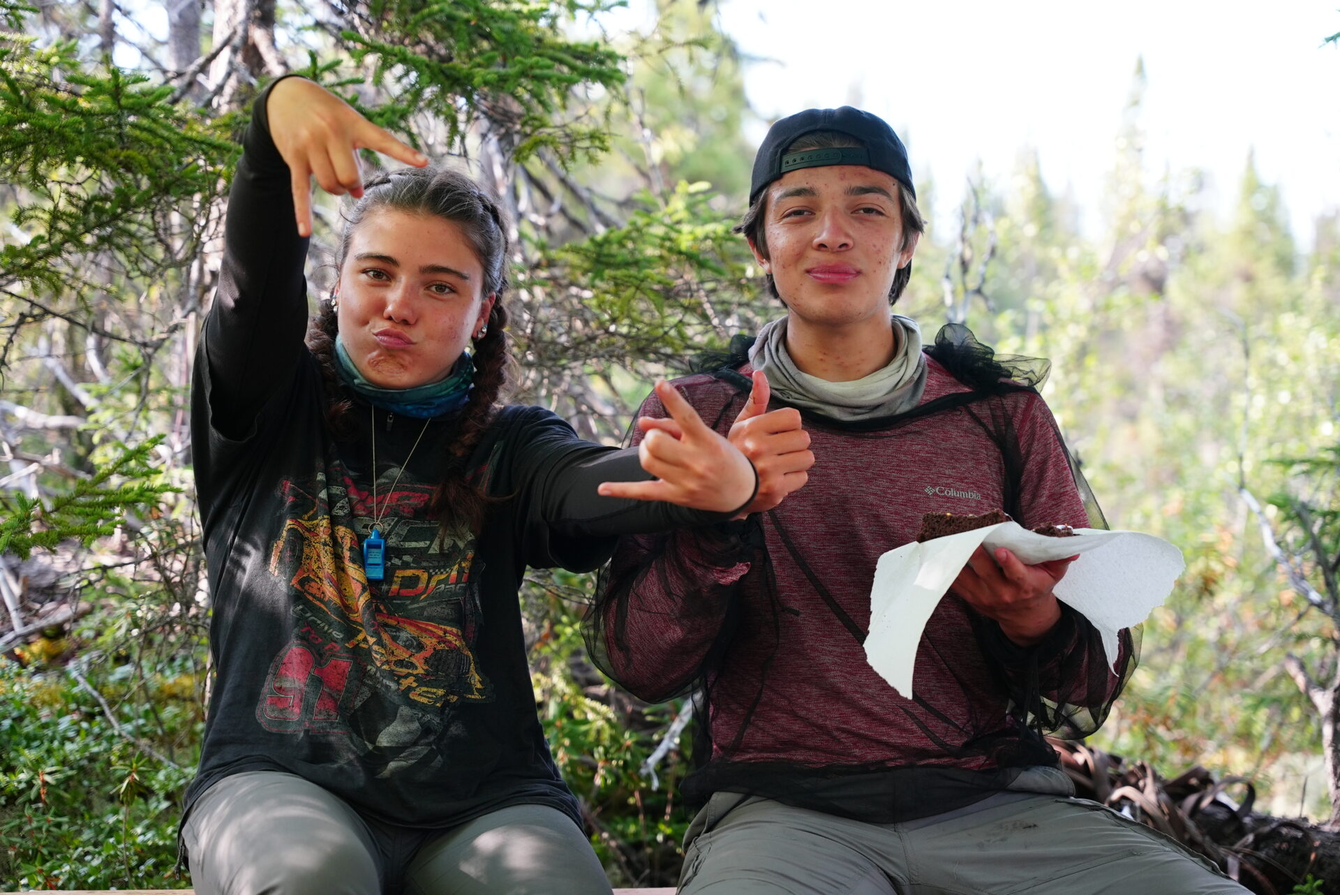 Two people posing outdoors in the woods.