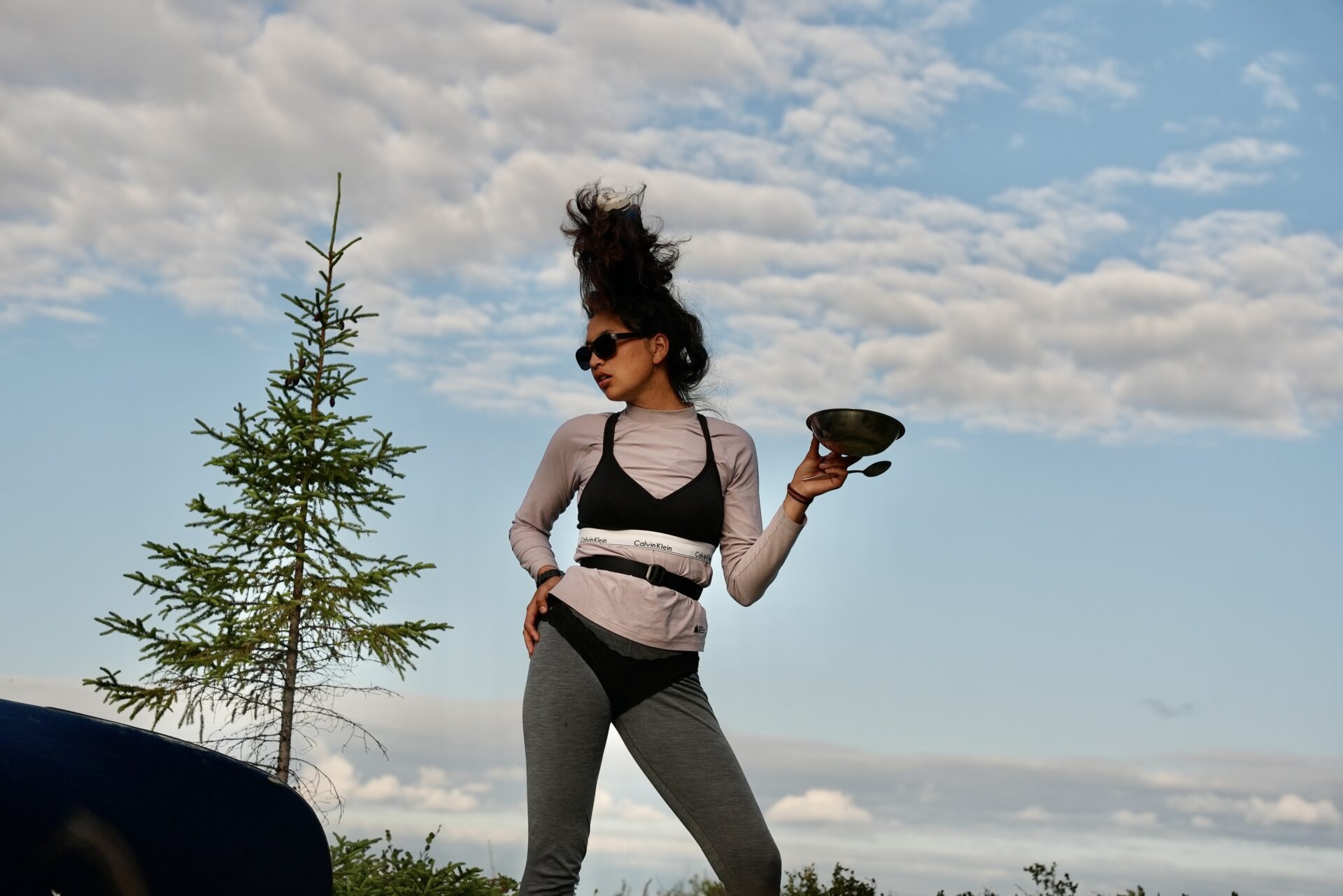 Woman holding bowl outdoors, wearing sunglasses