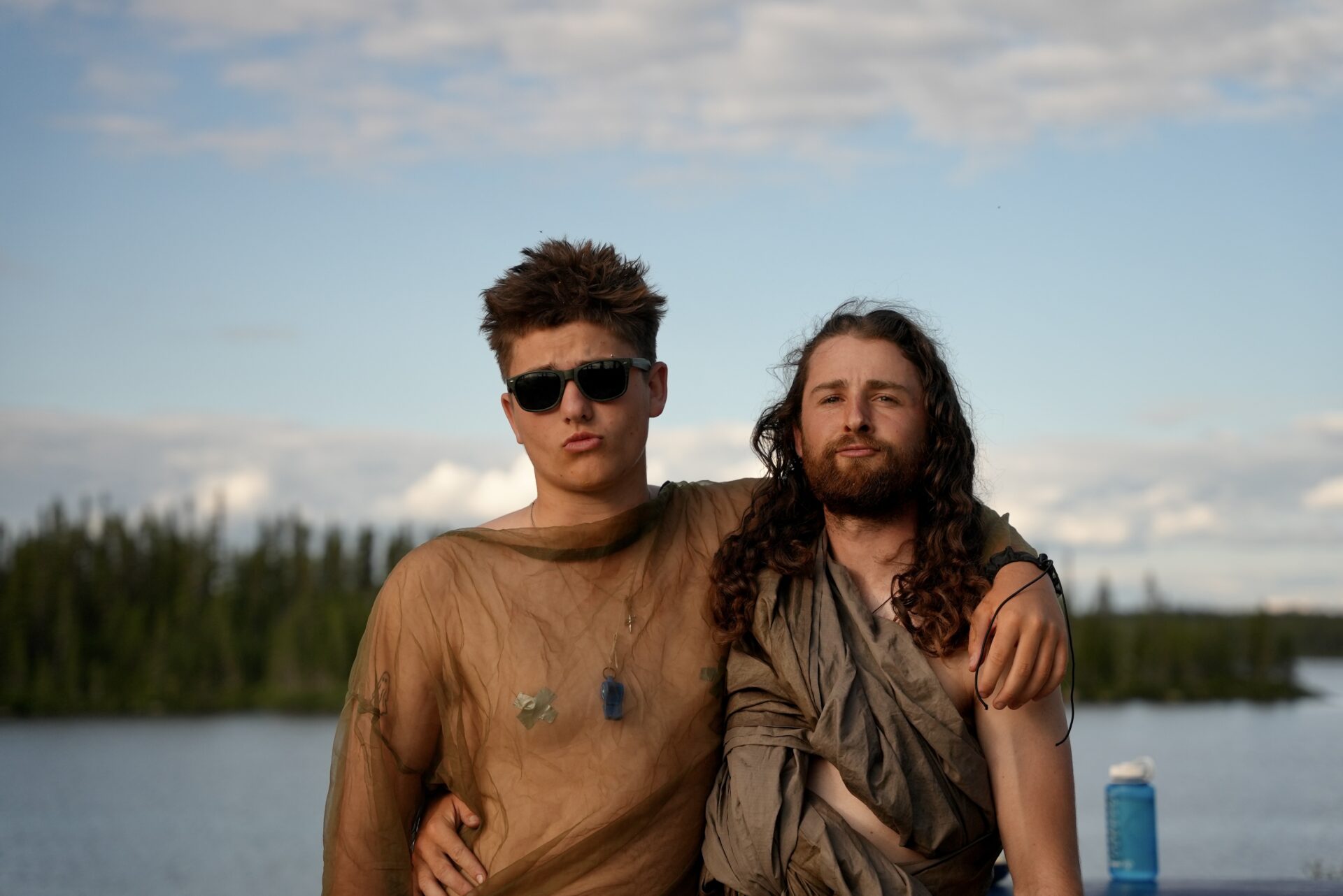 Two friends posing in front of a lake.