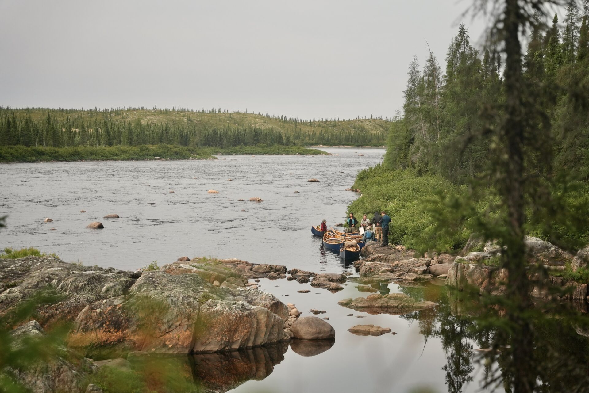 Group with canoes by a river.