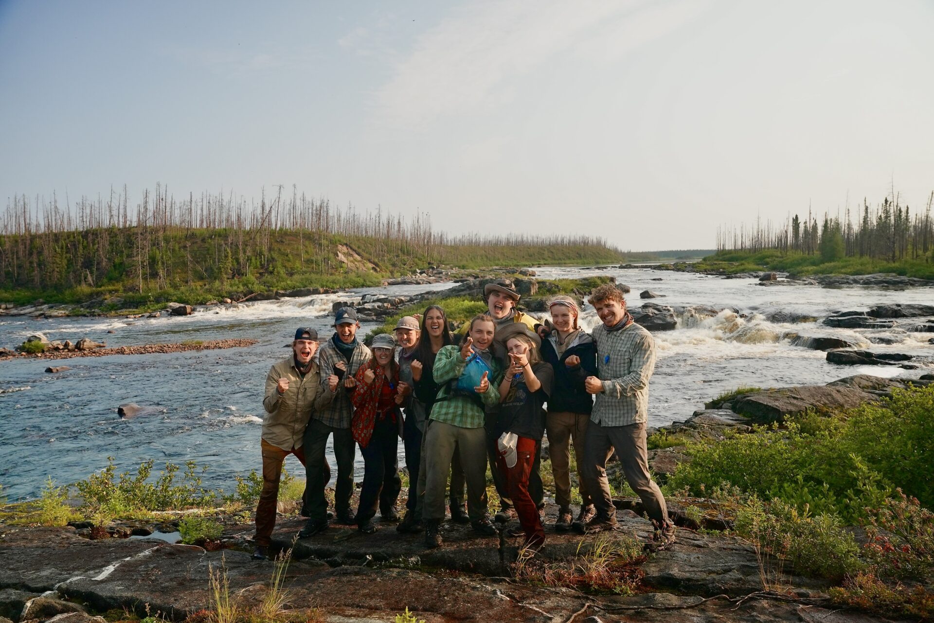 Group posing by a scenic riverside.