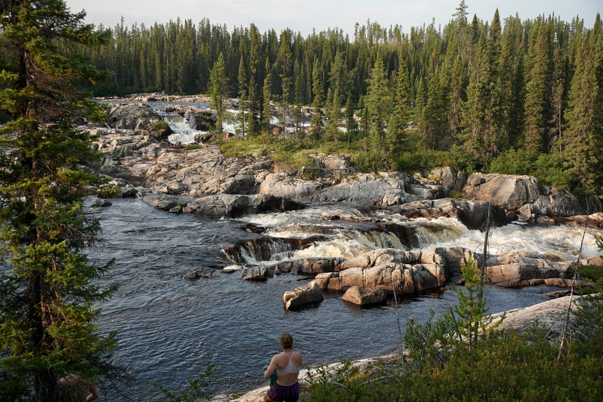 Person near rocks and river in forest.