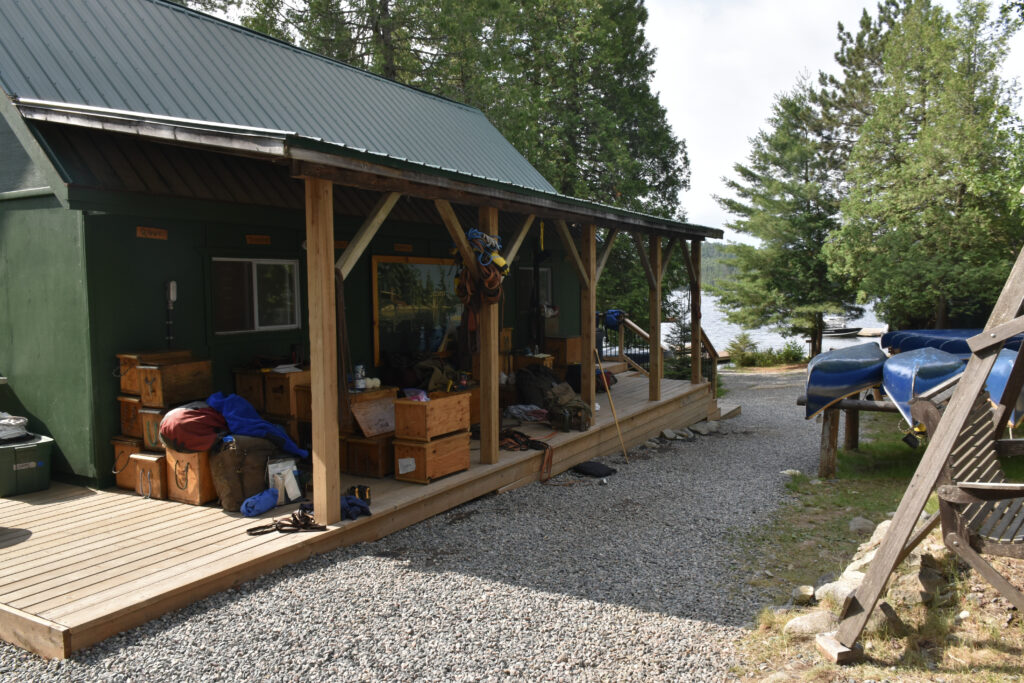 Cabin with canoes and lake in the background.