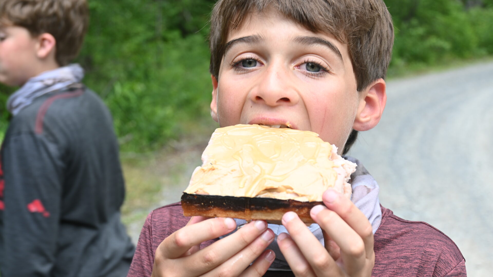 Child eating peanut butter sandwich outdoors