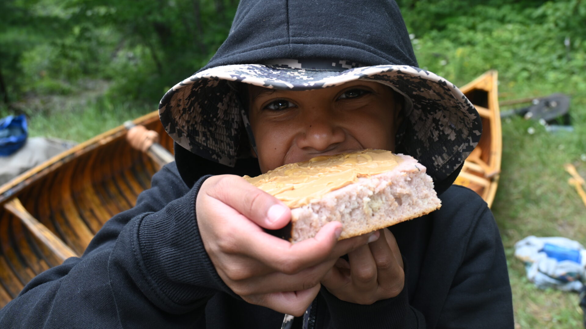 Child eating bread with peanut butter outdoors.