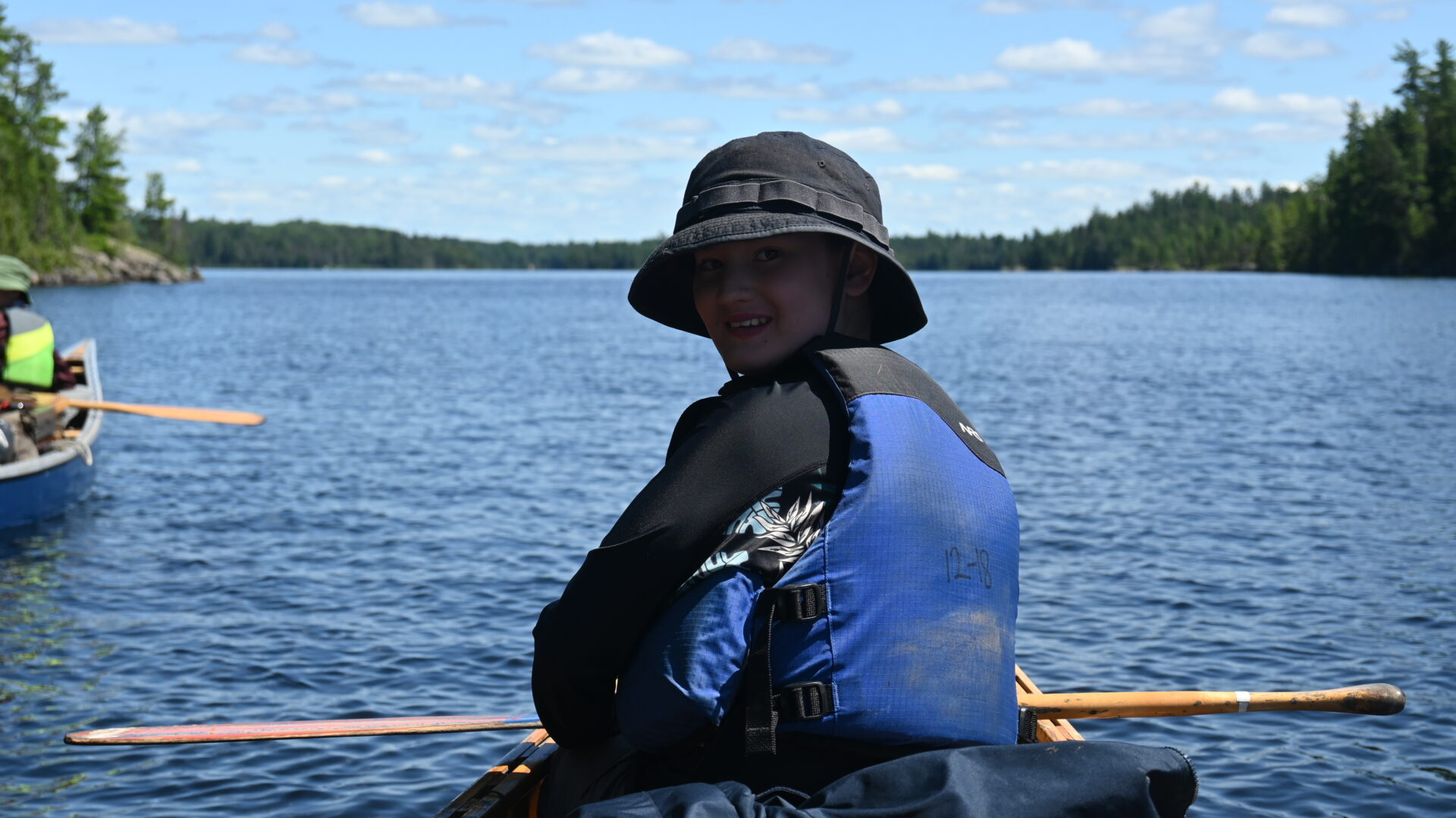 Child canoeing on a lake in summer.