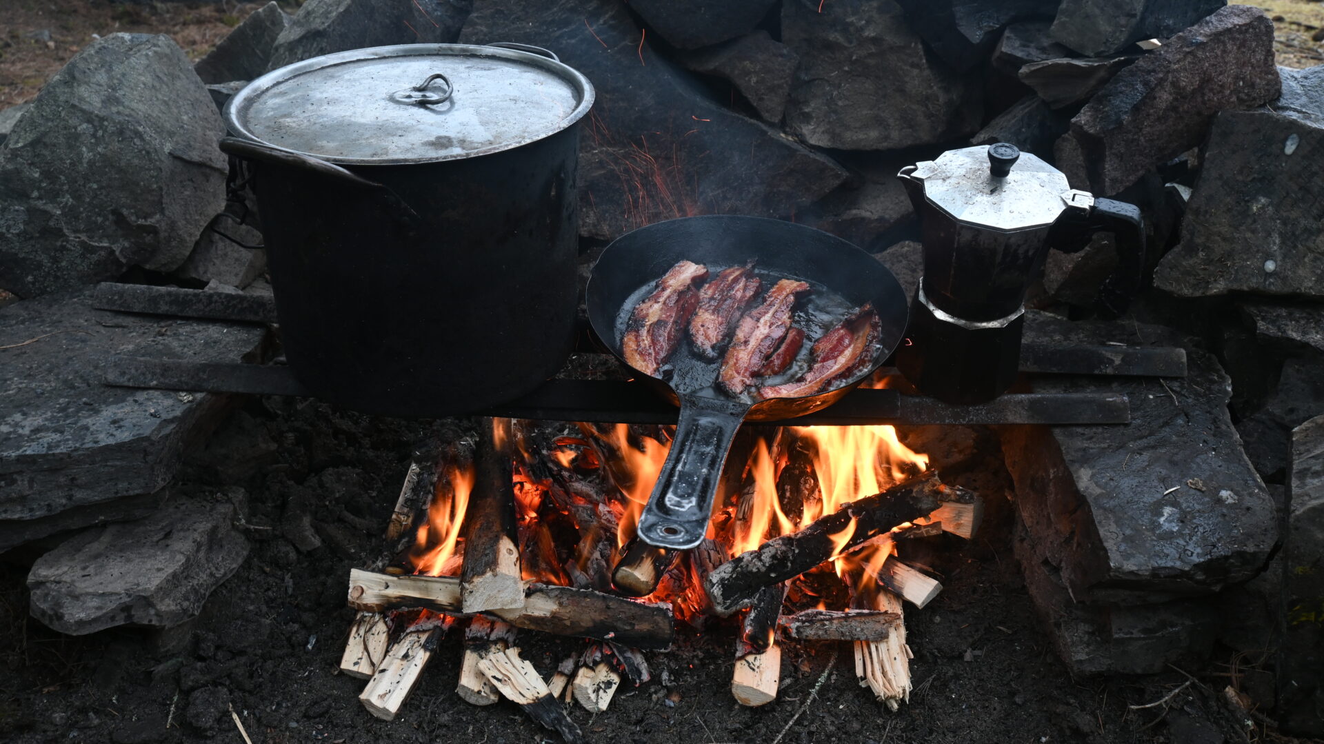 Cooking bacon and coffee over campfire.