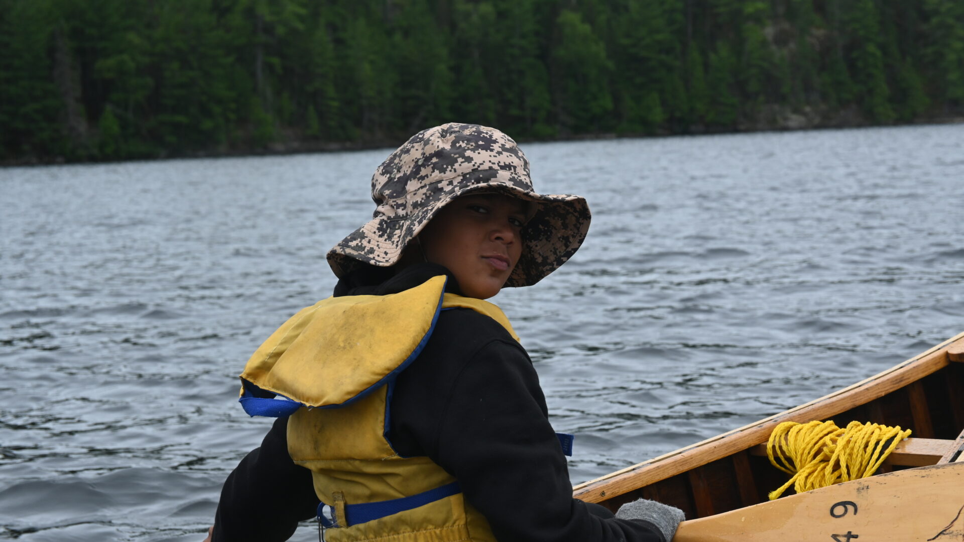 Person in camo hat boating on a lake.