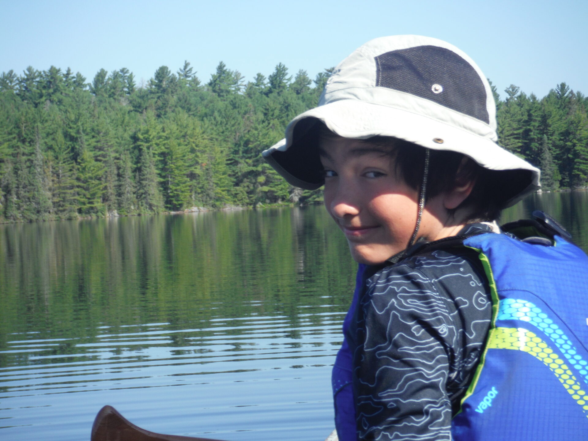 Boy smiling in canoe by forest lake