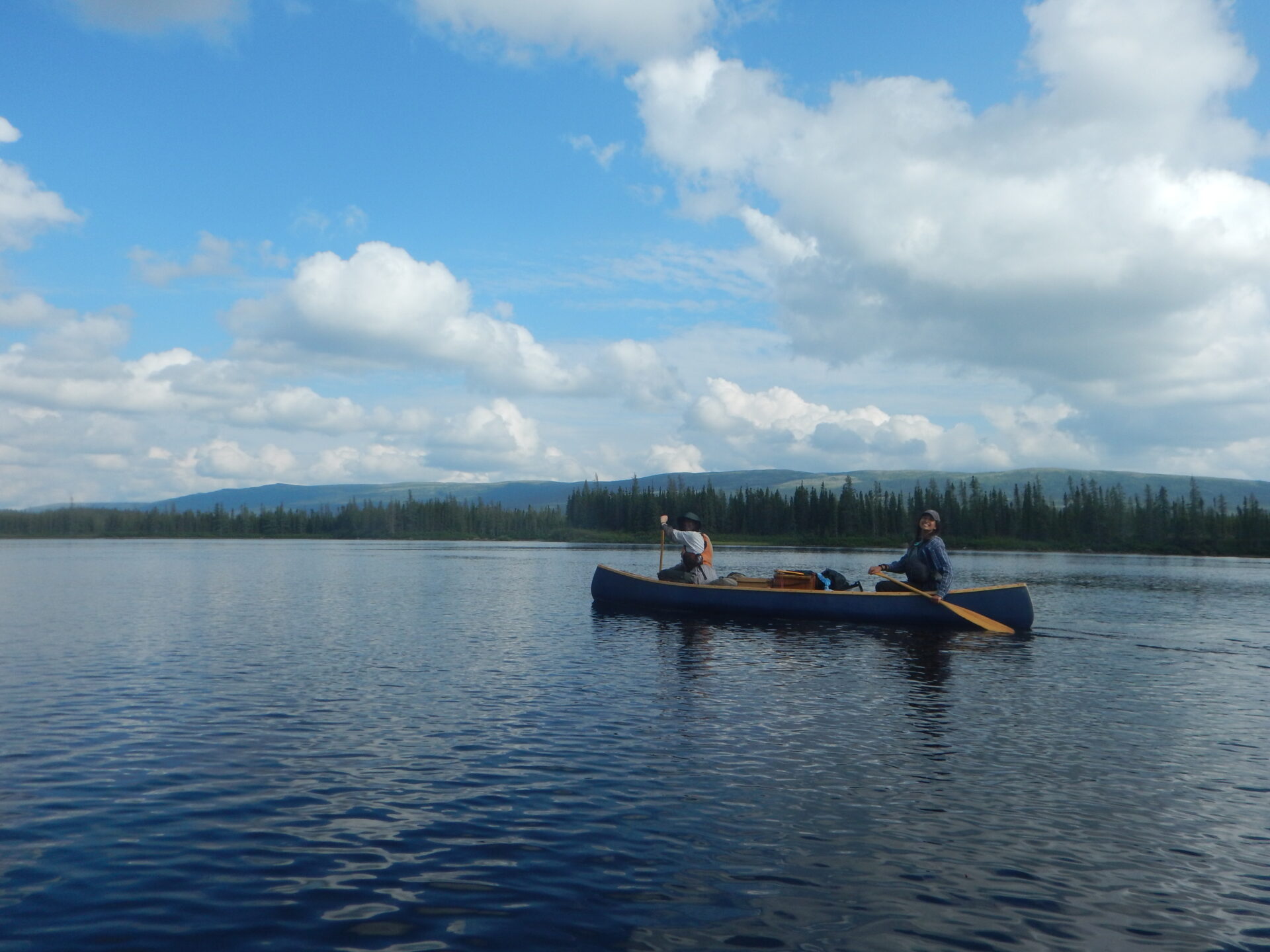 Two people canoeing on a calm lake.