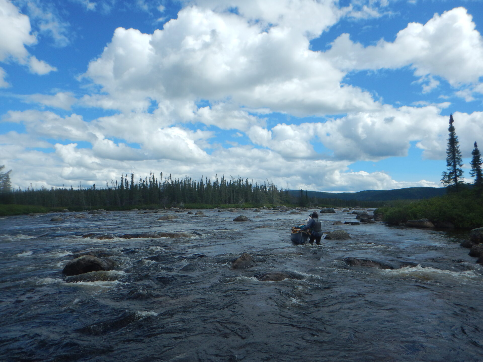 Person navigating river under cloudy sky