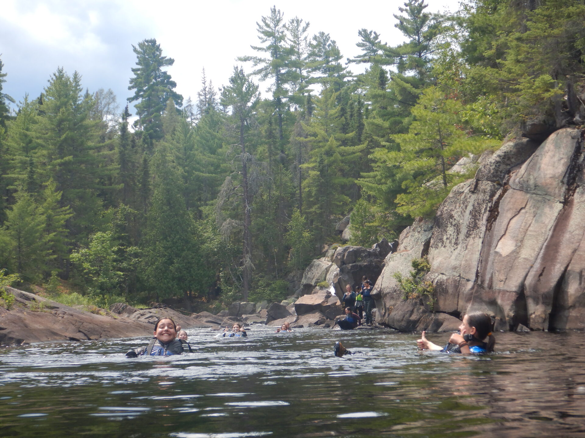 Group swimming in forest river with rocks