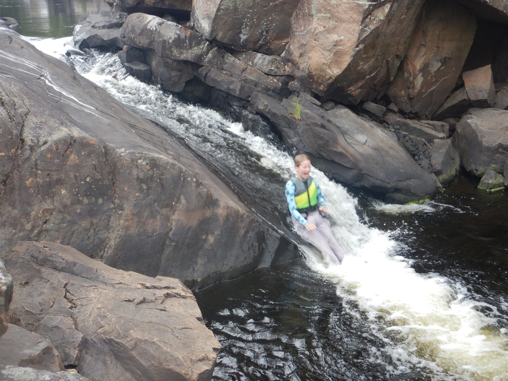 Person sliding down a rocky waterfall.