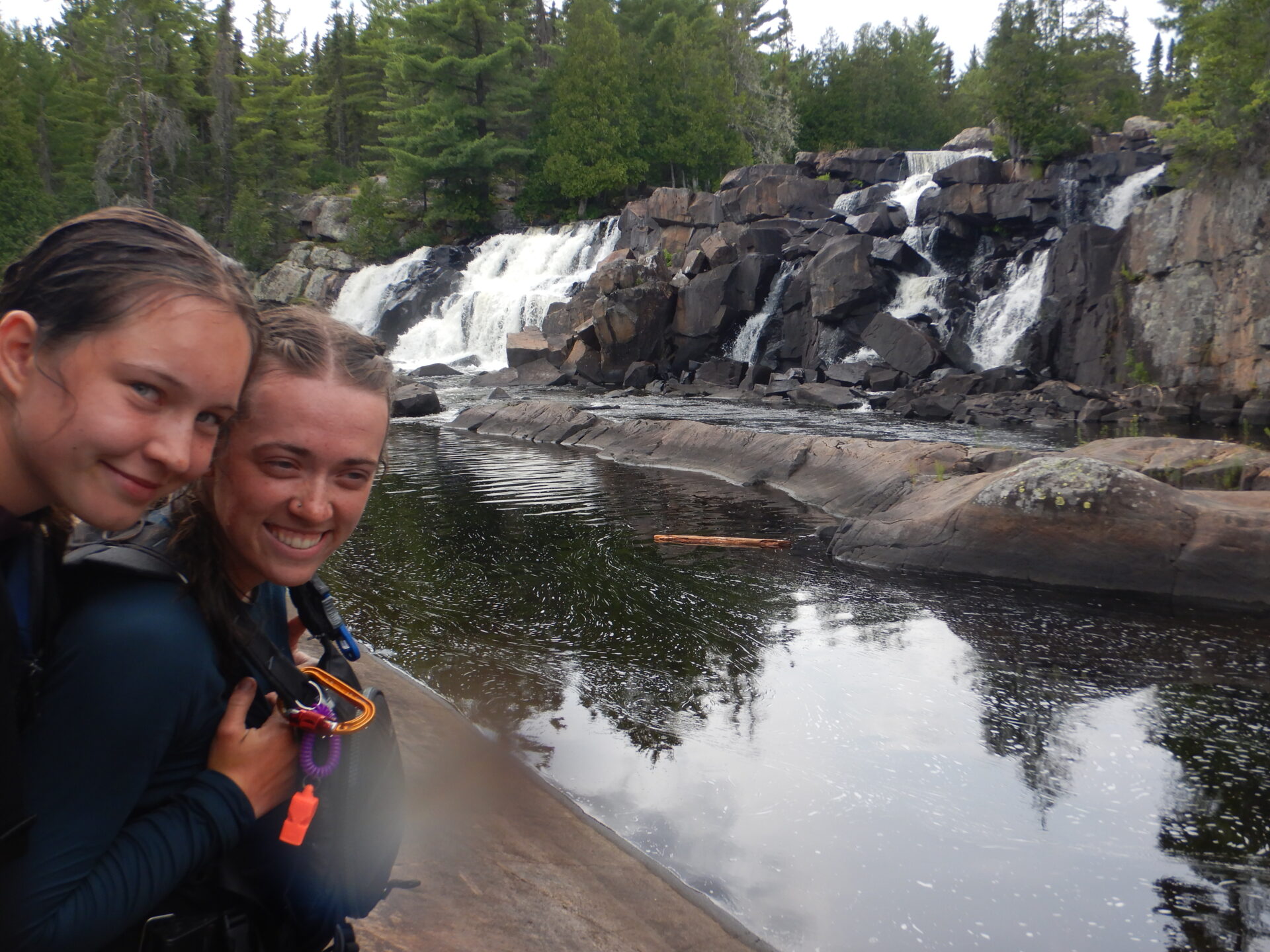 Two people smiling near a waterfall.