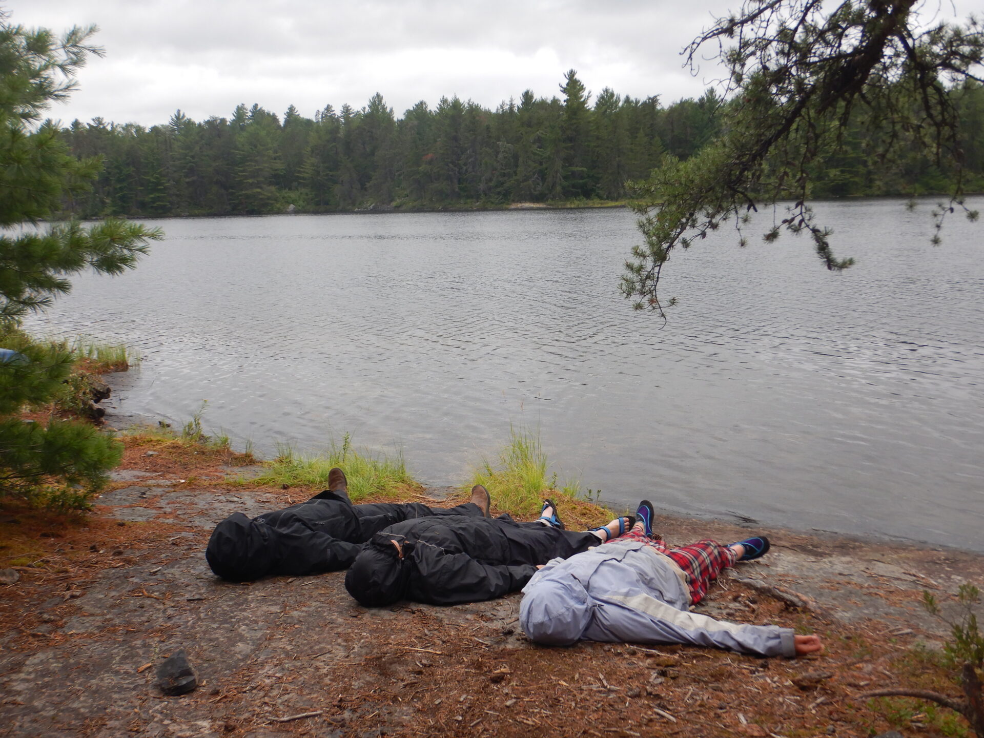 People resting near a calm lake in nature.