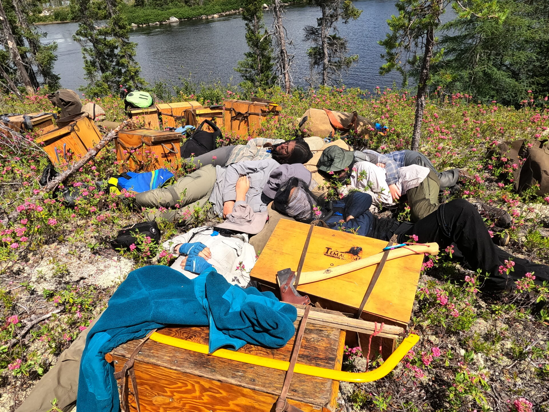 Hikers resting near a lake with gear.