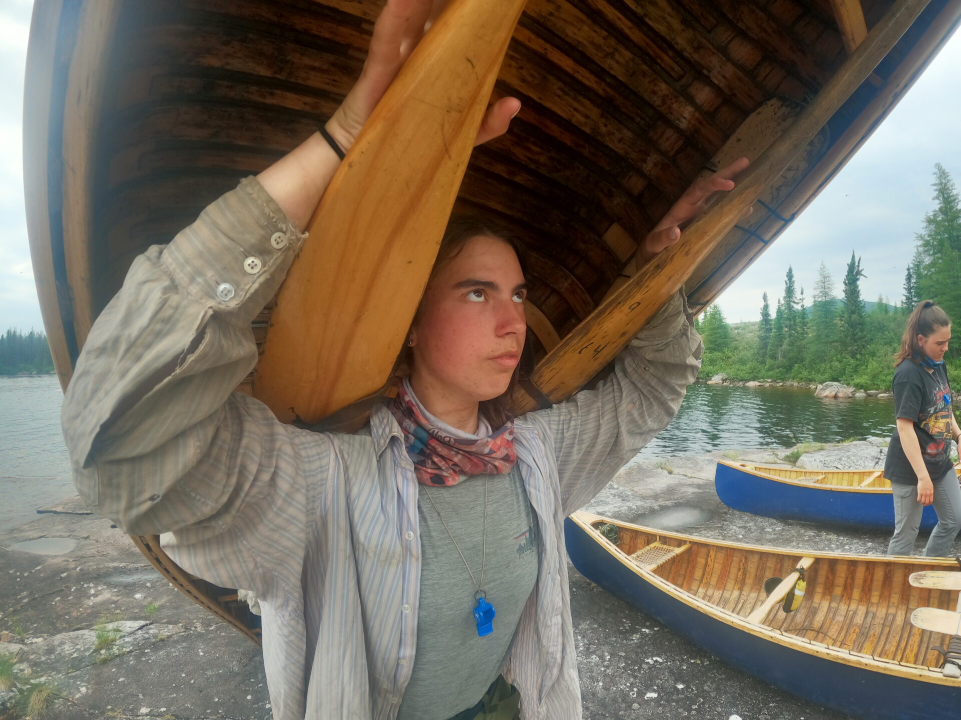 Person carrying canoe near a lake