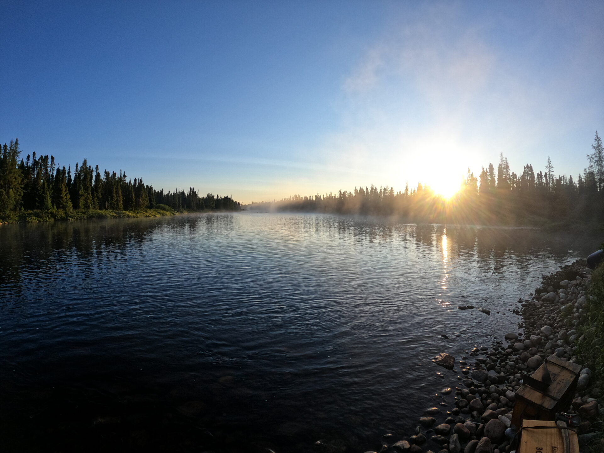 Sunrise over a lake with trees.