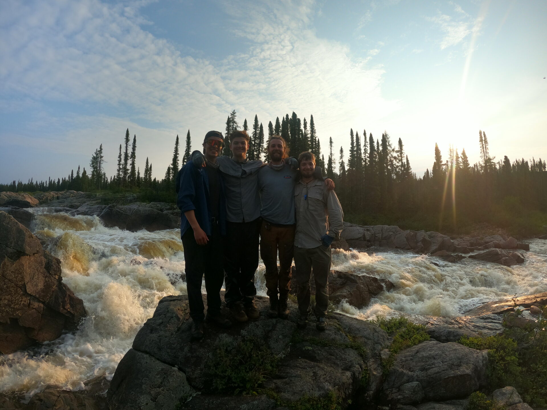 Friends posing by a scenic river waterfall.