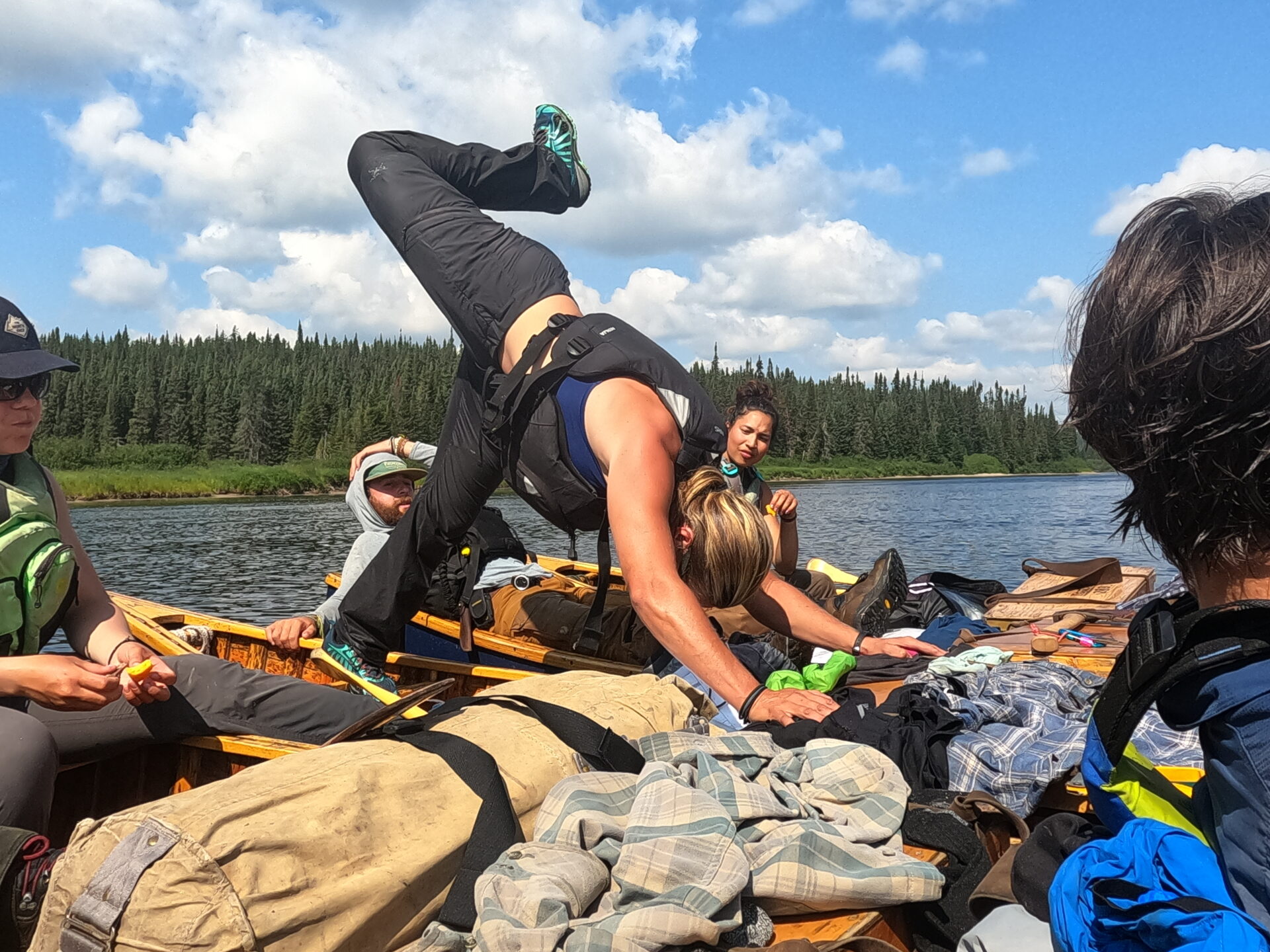 People balancing on a canoe in a river.