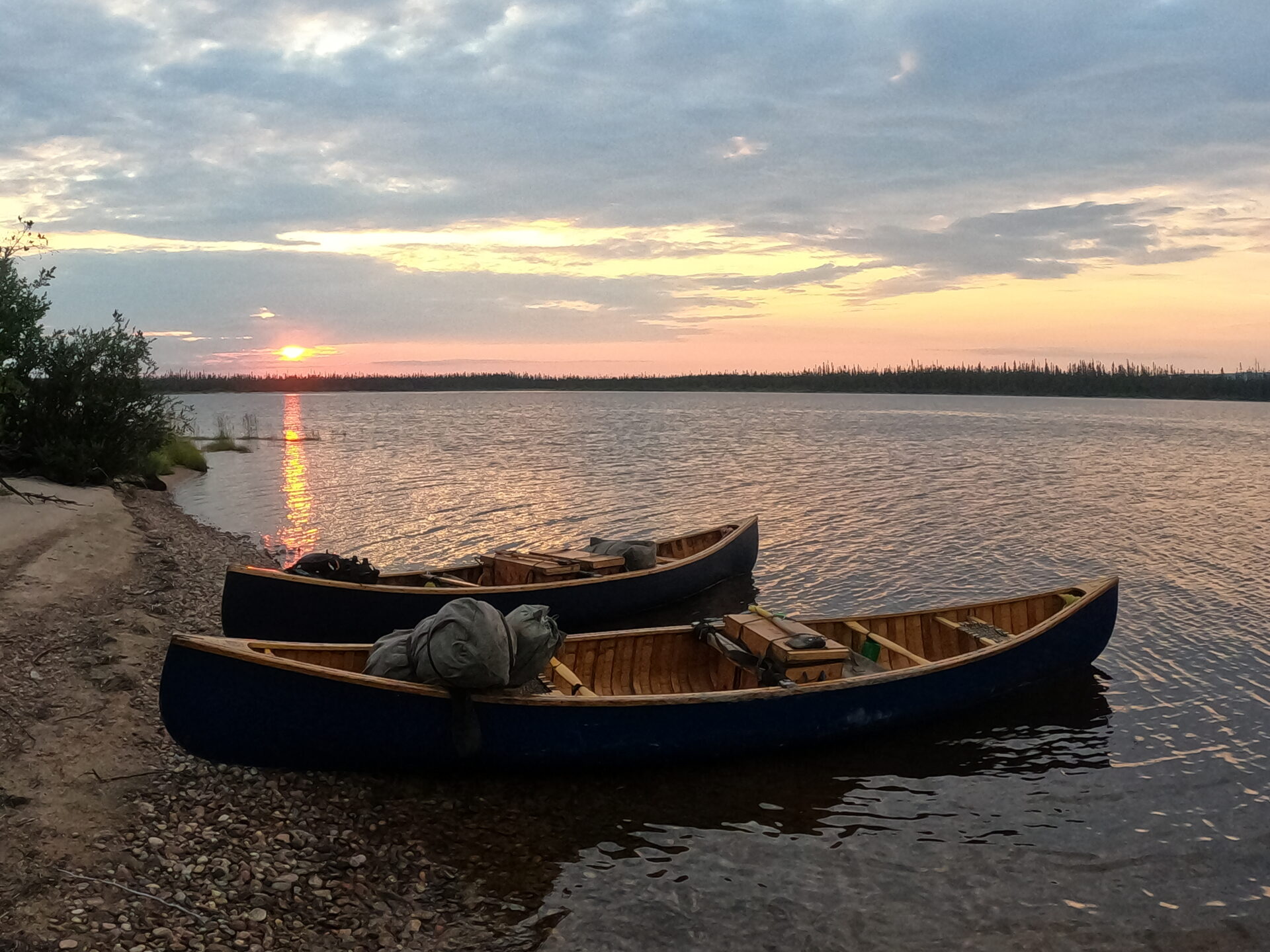 Sunset over lake with two docked canoes.