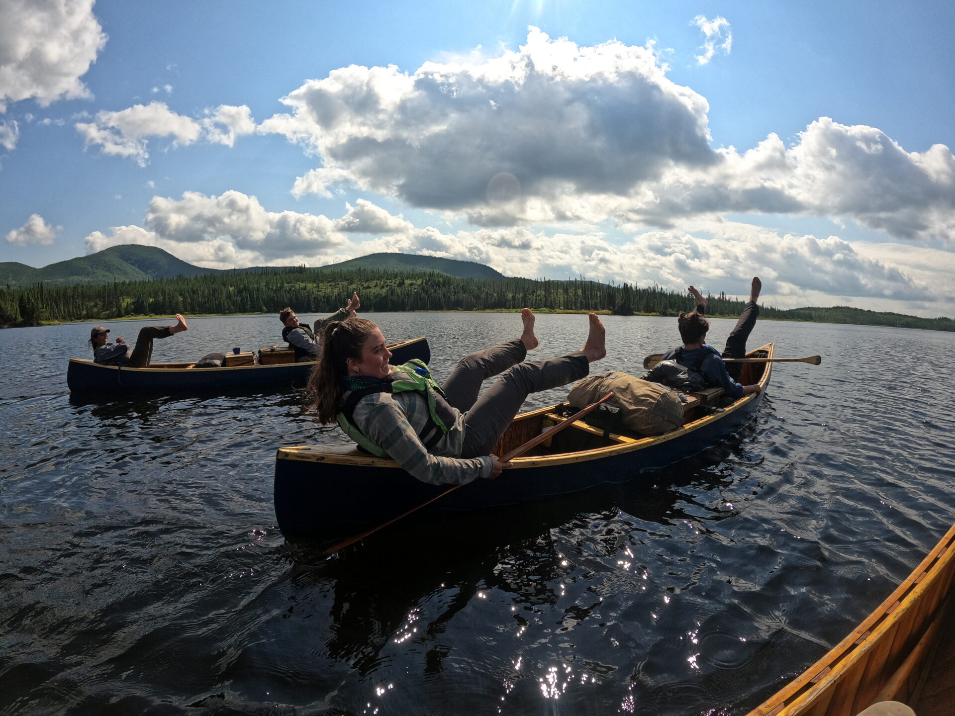 People canoeing on a lake under a sunny sky.