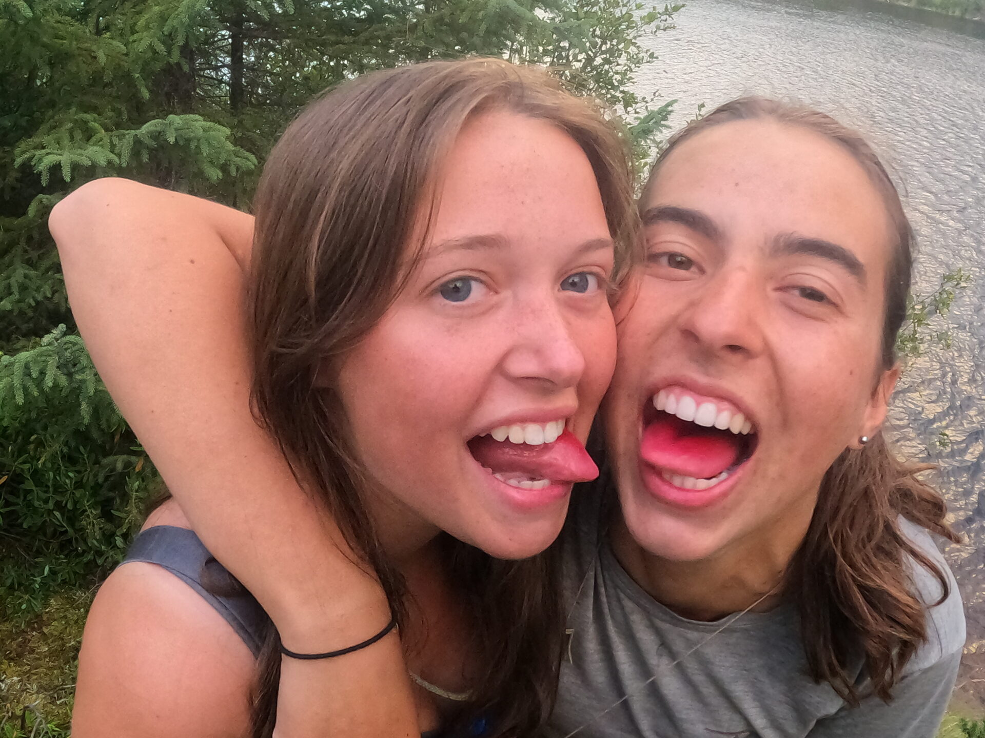 Two friends smiling and sticking out tongues