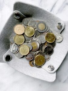 Tray of assorted currency coins on marble surface.