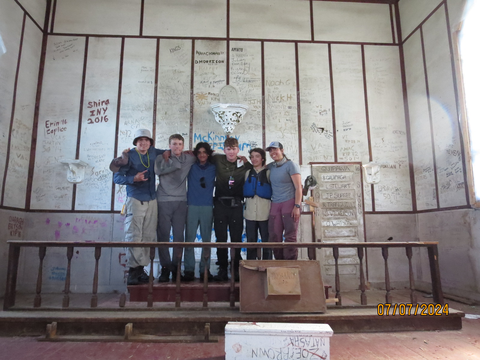 Group of people inside a graffitied room.