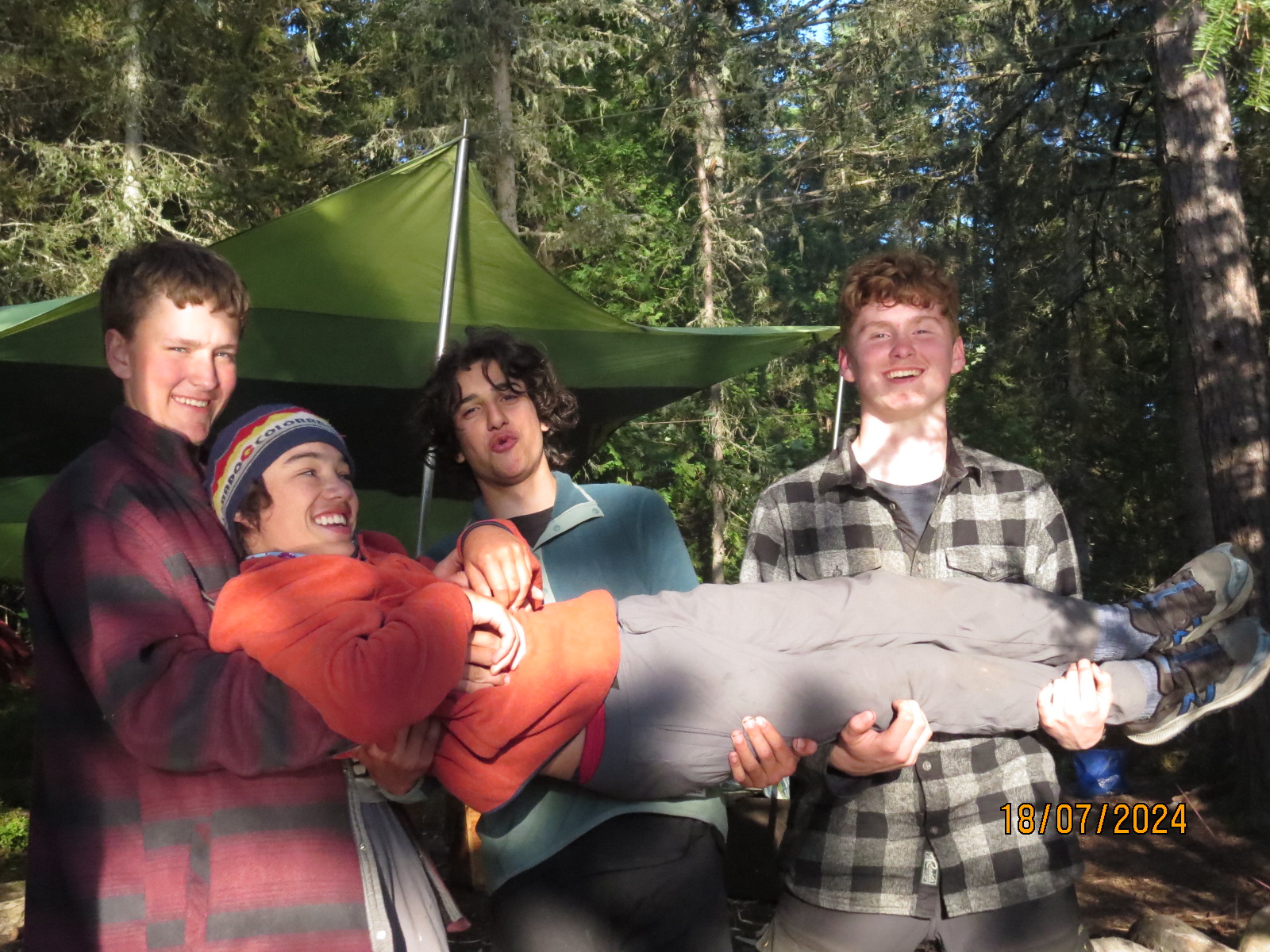 Group of friends lifting one person in forest