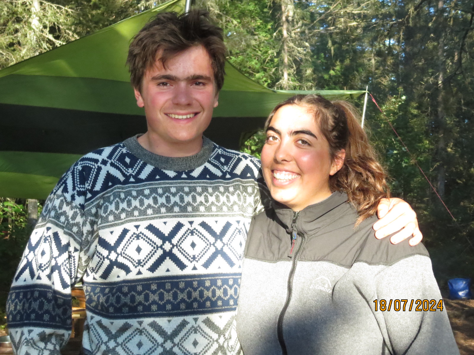 Two friends smiling outside at campsite, July 2024.