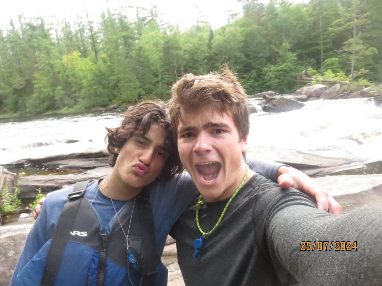 Two friends posing by a river.