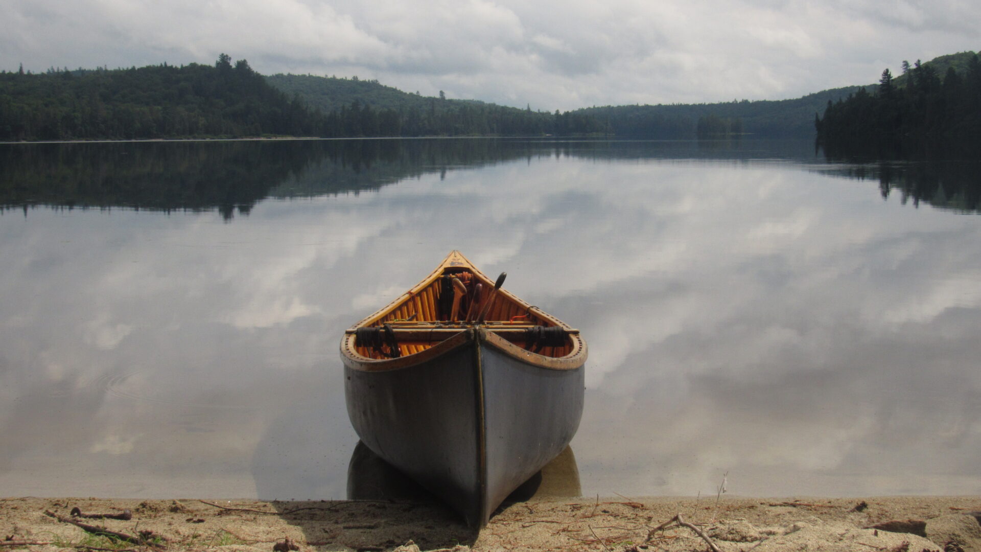 Canoe on calm lake with forested hills