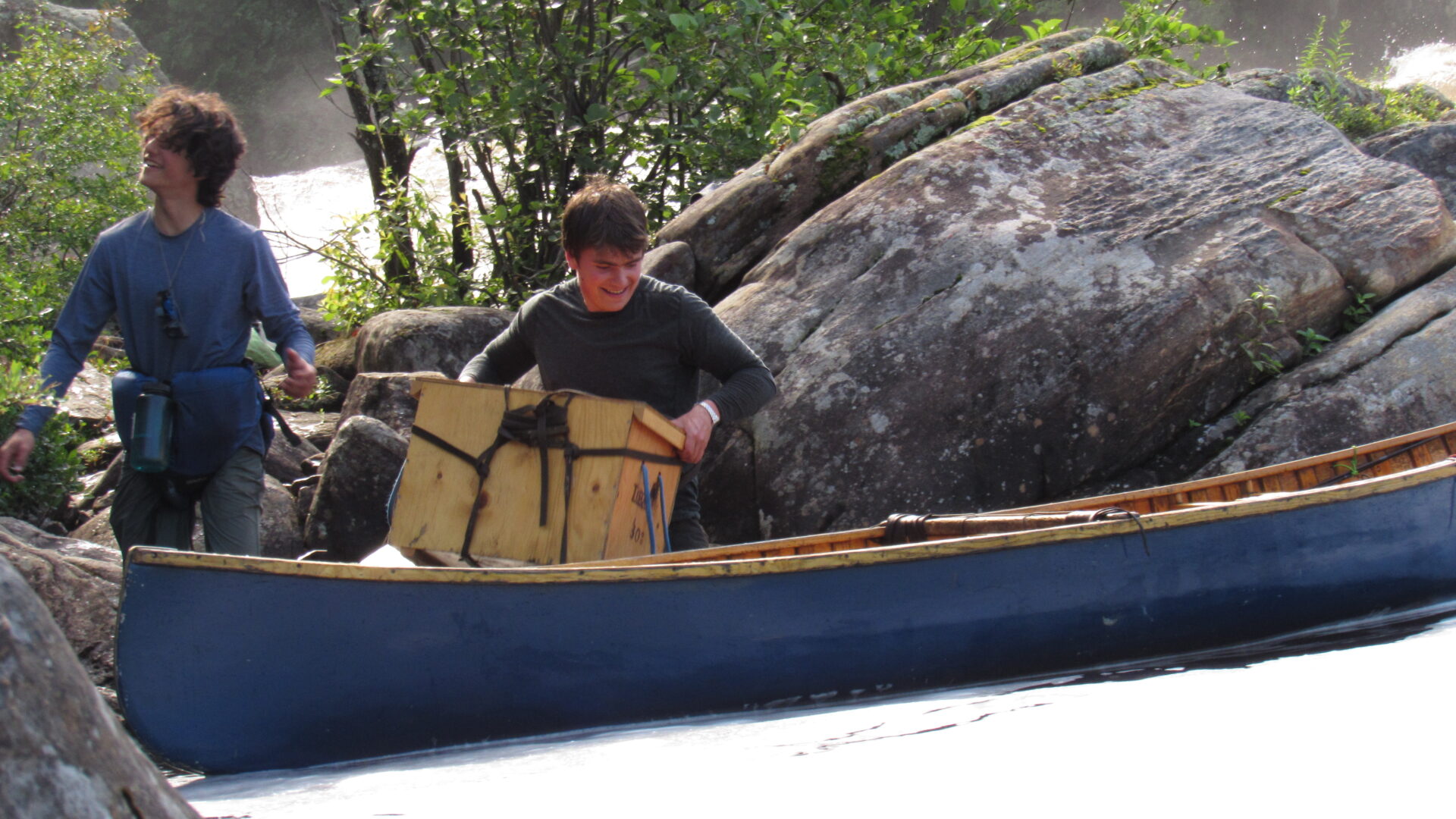 Two people with a canoe in a rocky forest