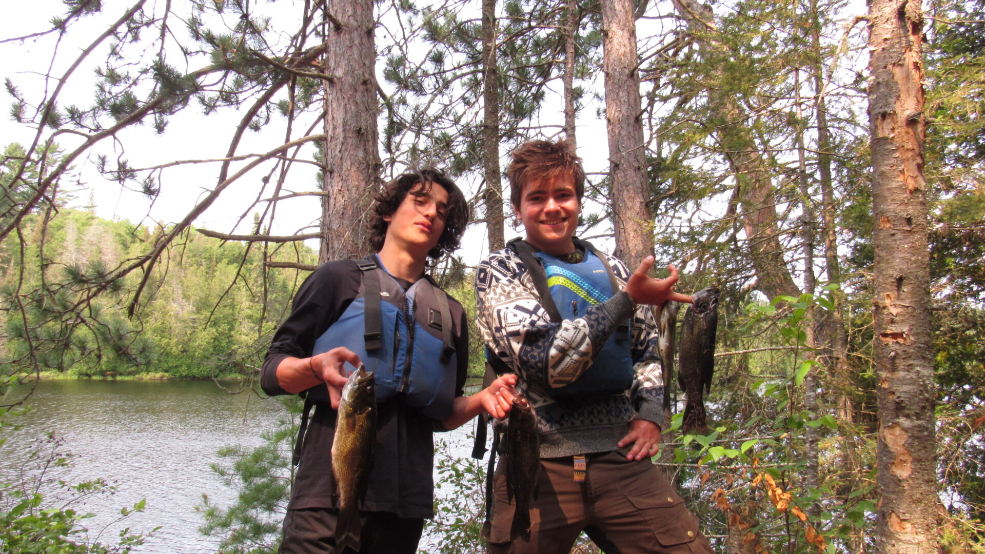 Two people holding fish in a forest.