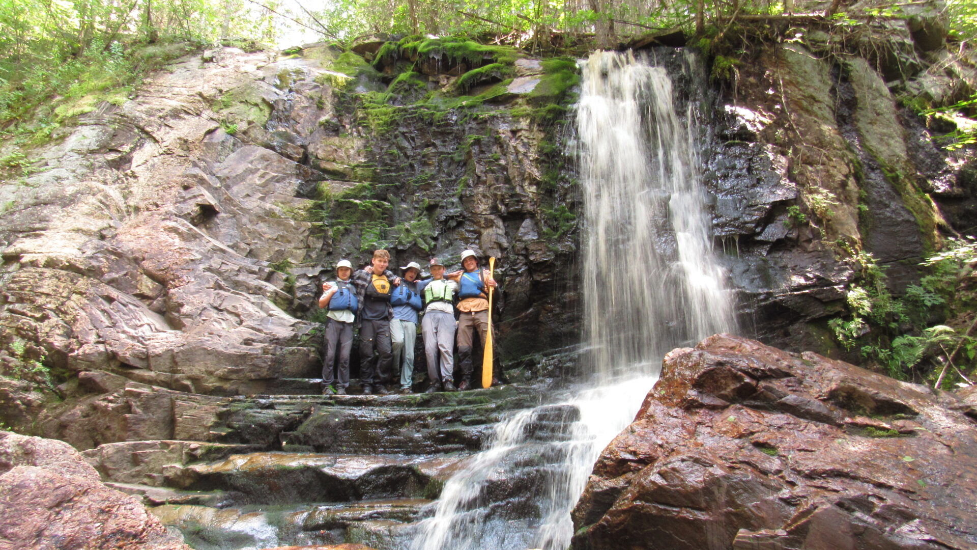 Group posing by forest waterfall