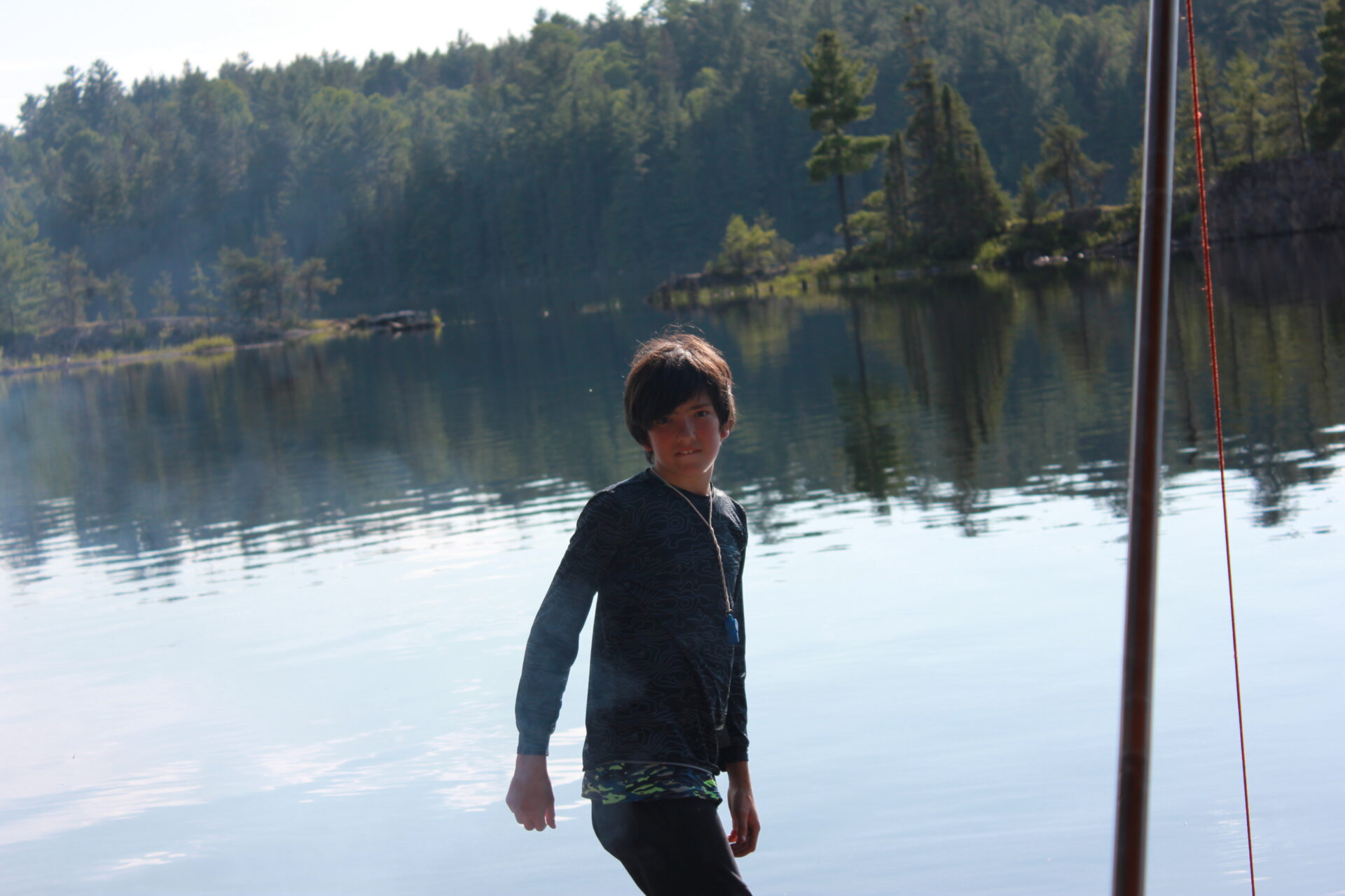 Young boy standing by a serene lake.