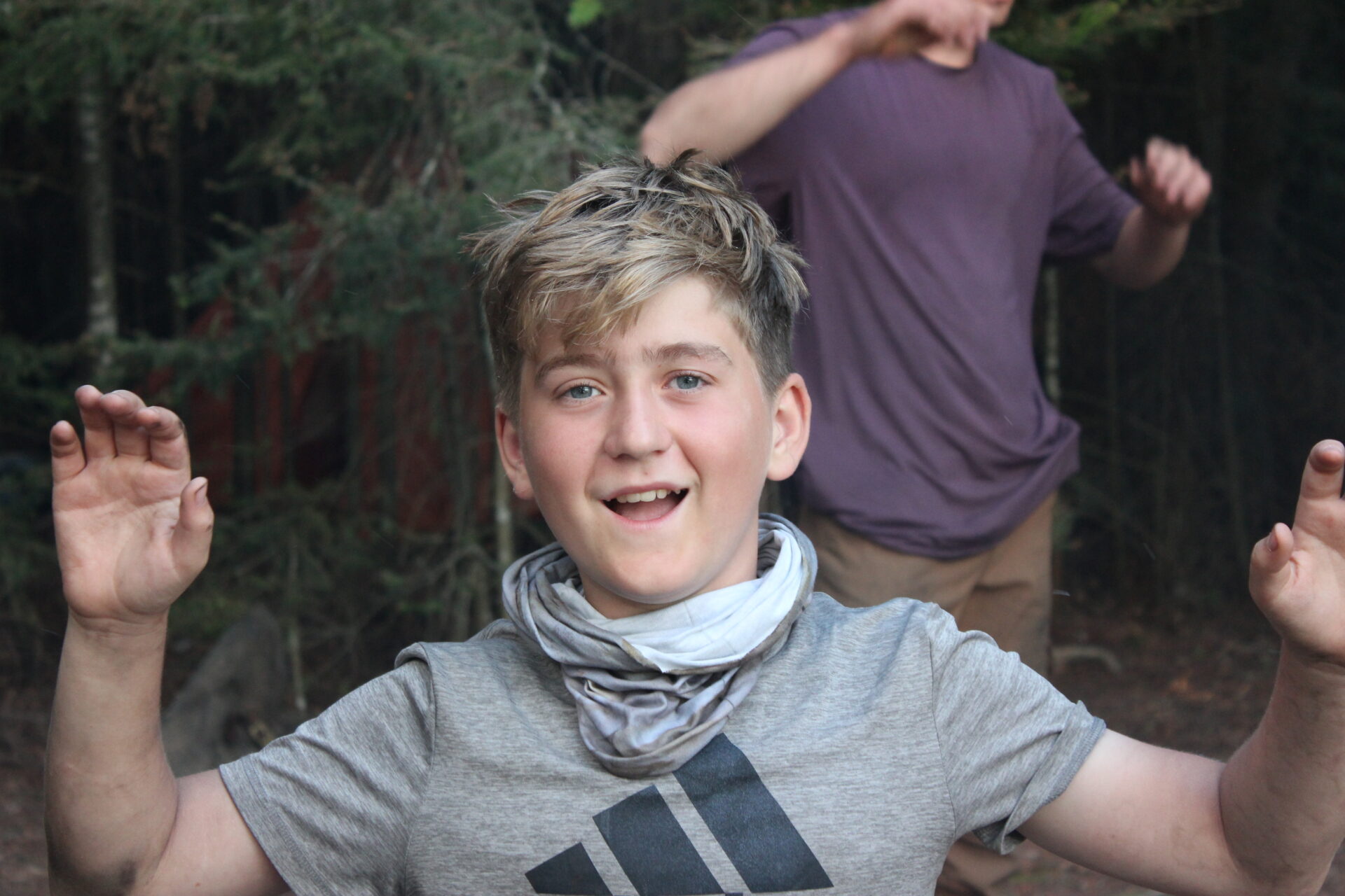 Boy smiling and raising hands outdoors