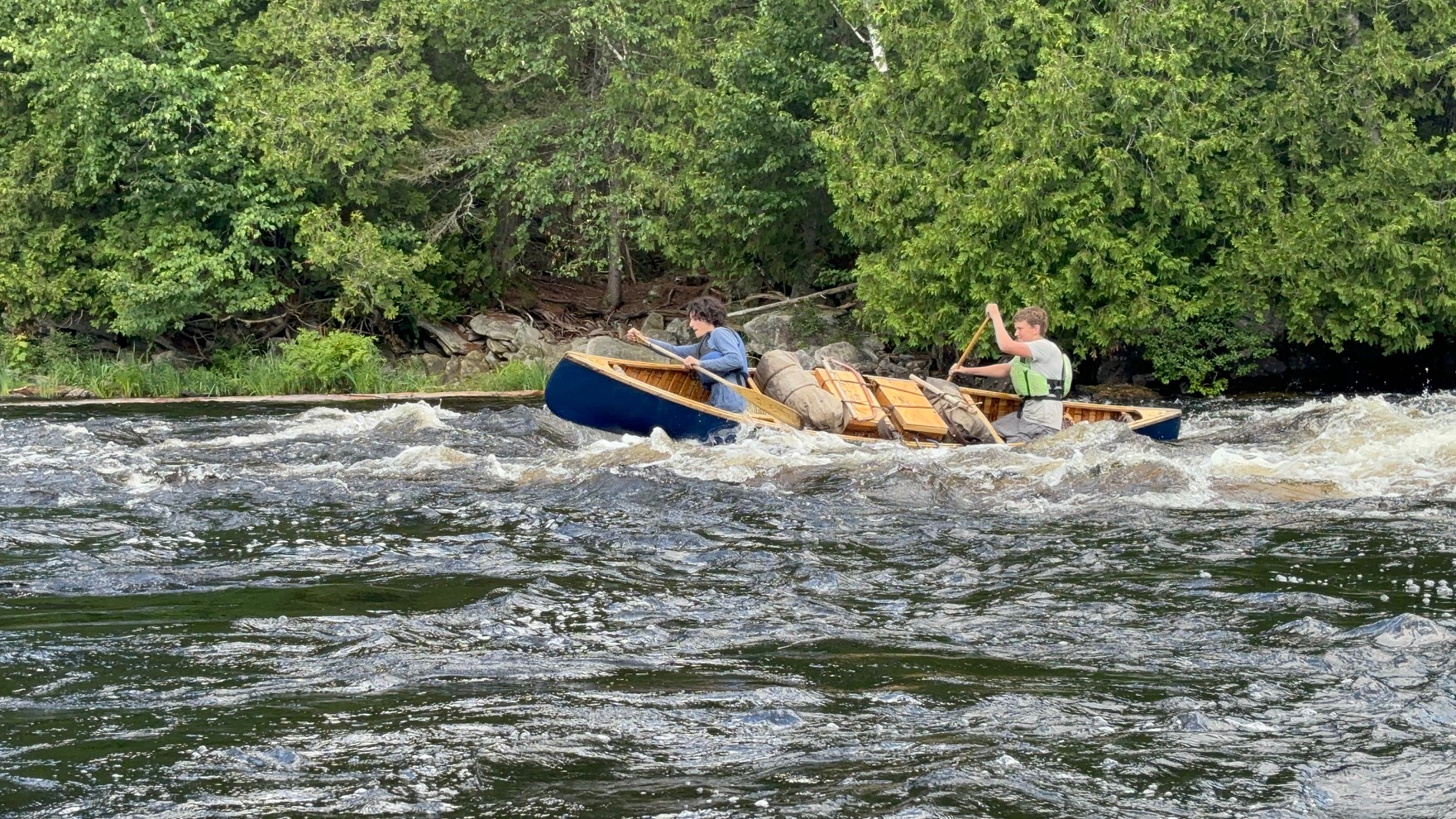 Two people canoeing in a river with rapids.