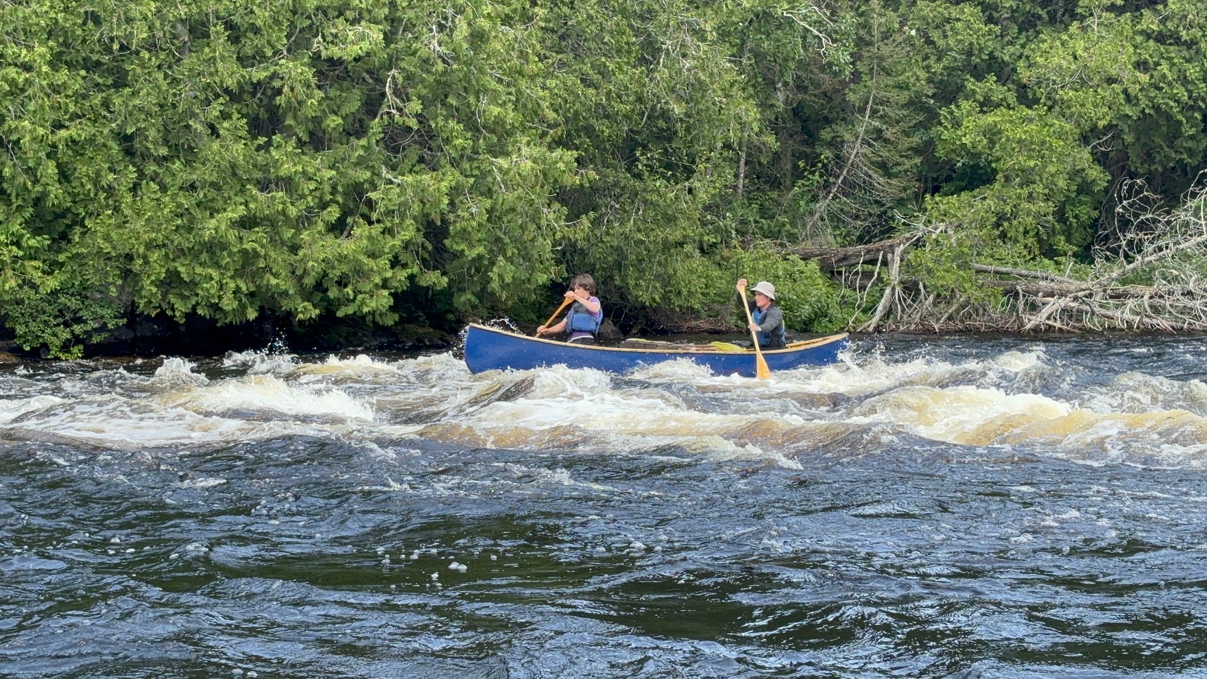 Two people canoeing through whitewater rapids