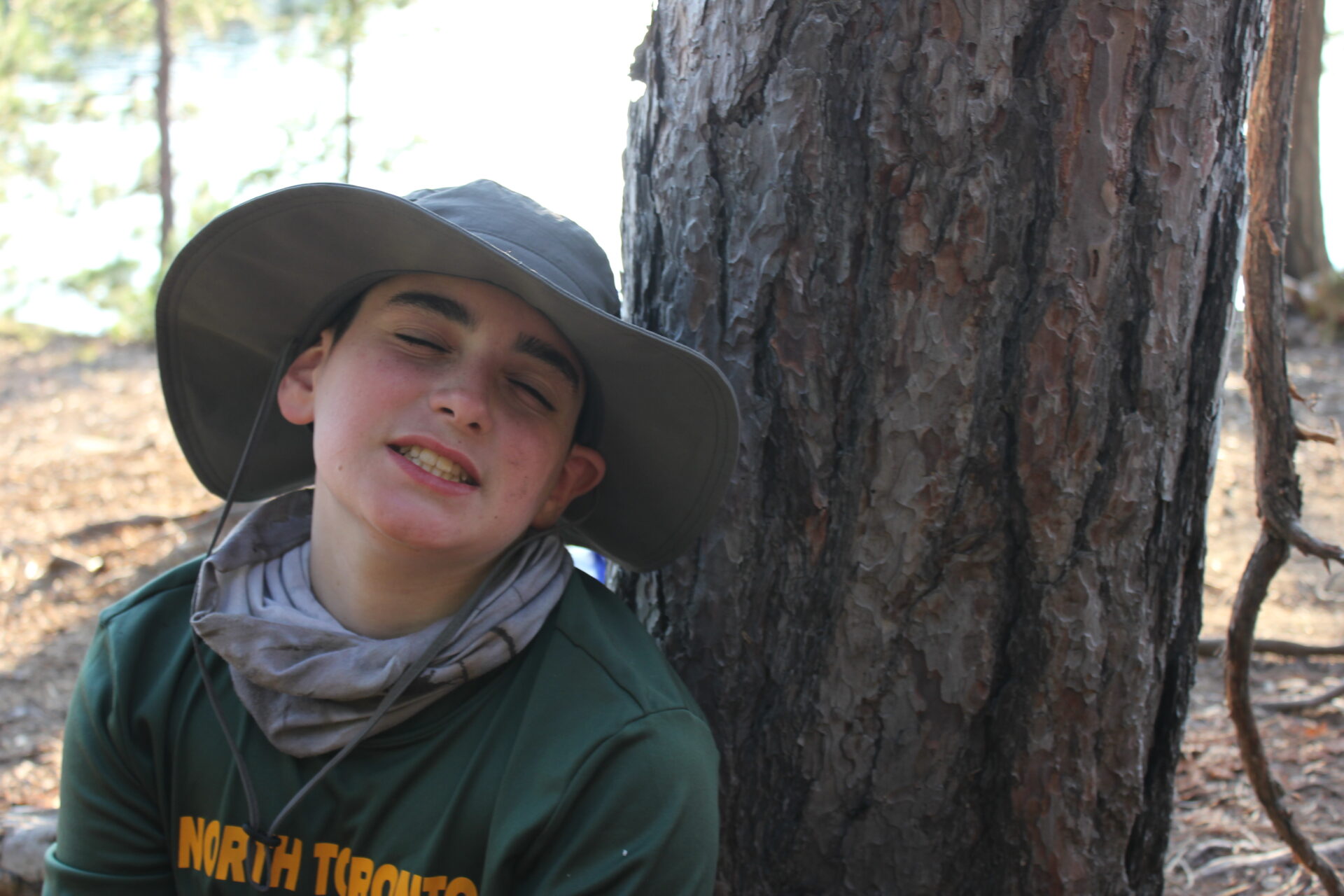 Person resting against tree in outdoor setting