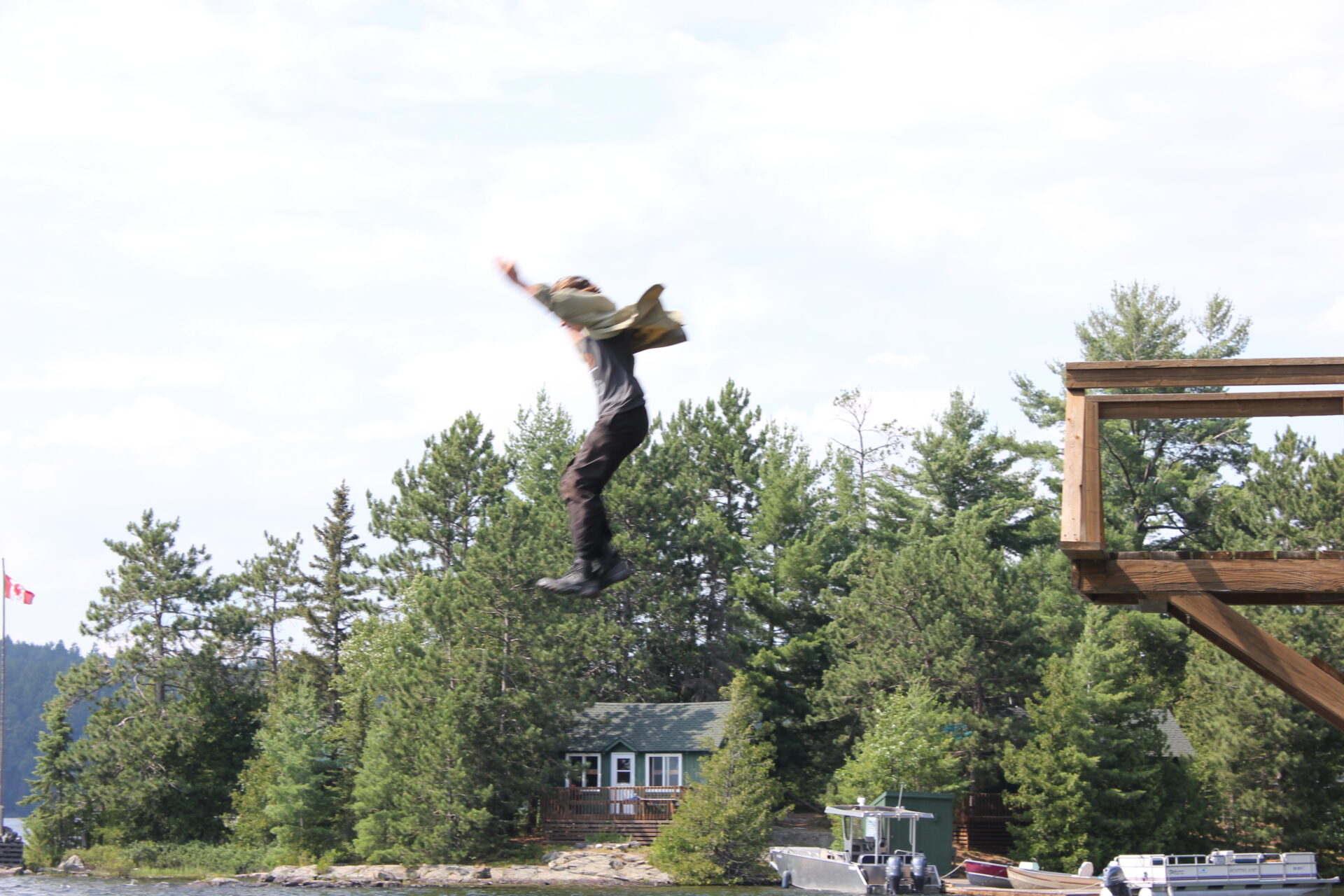 Person jumping off a wooden platform into nature.