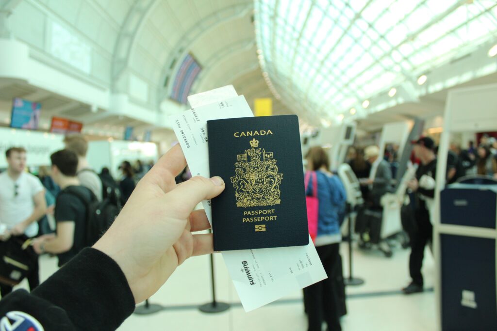 Hand holding Canadian passport and boarding pass at airport.