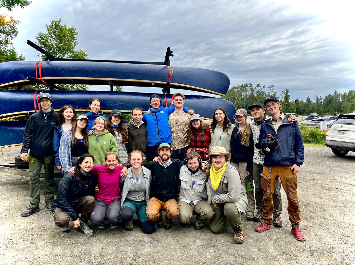 Group photo with canoes and trees in background.