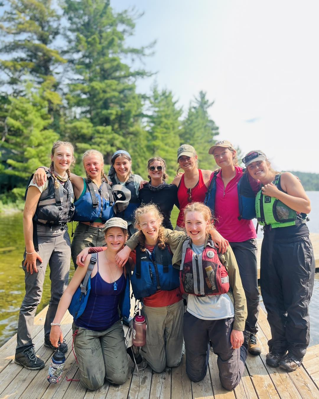 Group of friends in life jackets on a dock.